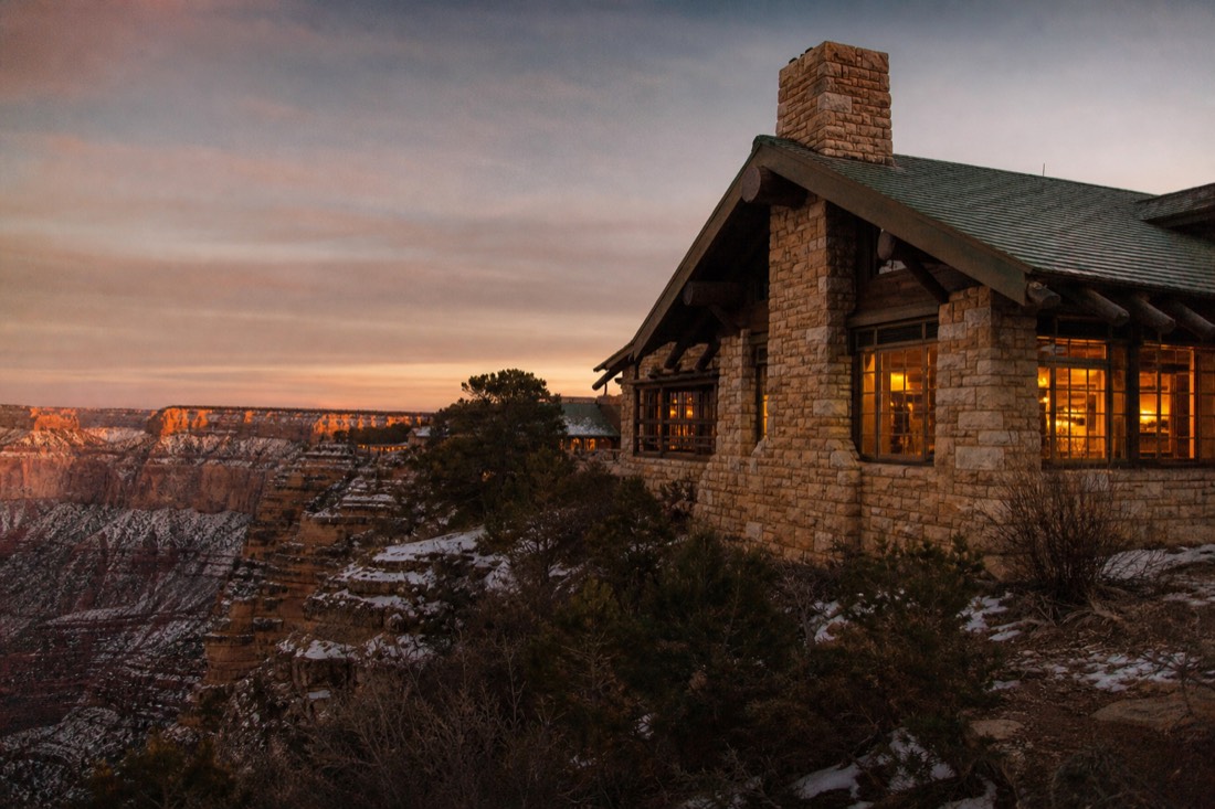 Warm lamplit windows of a historic stone and timber lodge at the South Rim village on a winter evening