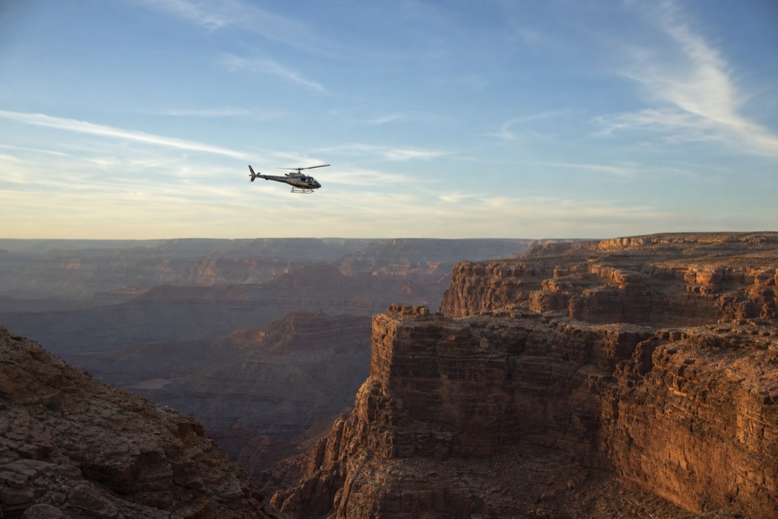 A helicopter following a set route high above the canyon rim under a wide blue sky