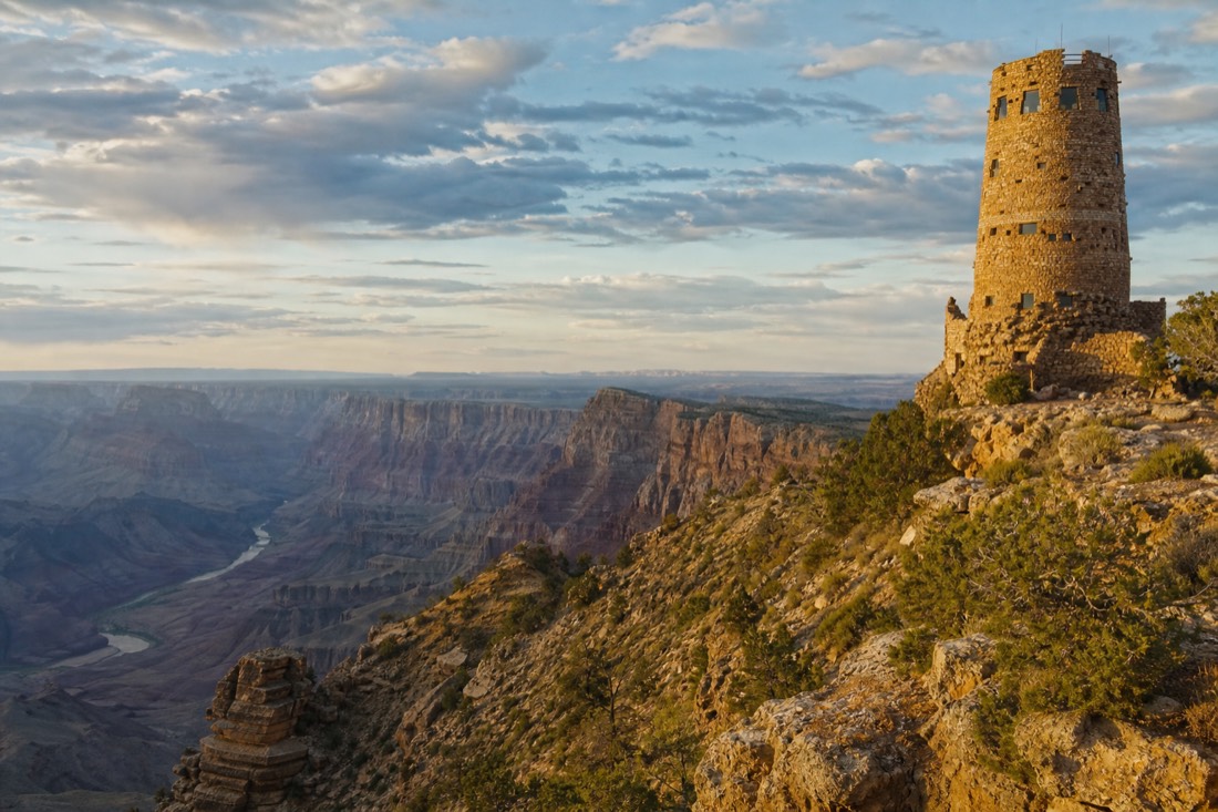 The stone Desert View Watchtower standing on the canyon rim with the Colorado River visible far below