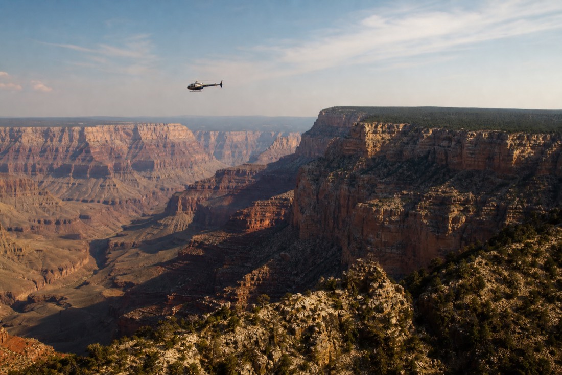 Helicopter crossing the widest part of the Grand Canyon with the forested North Rim plateau ahead