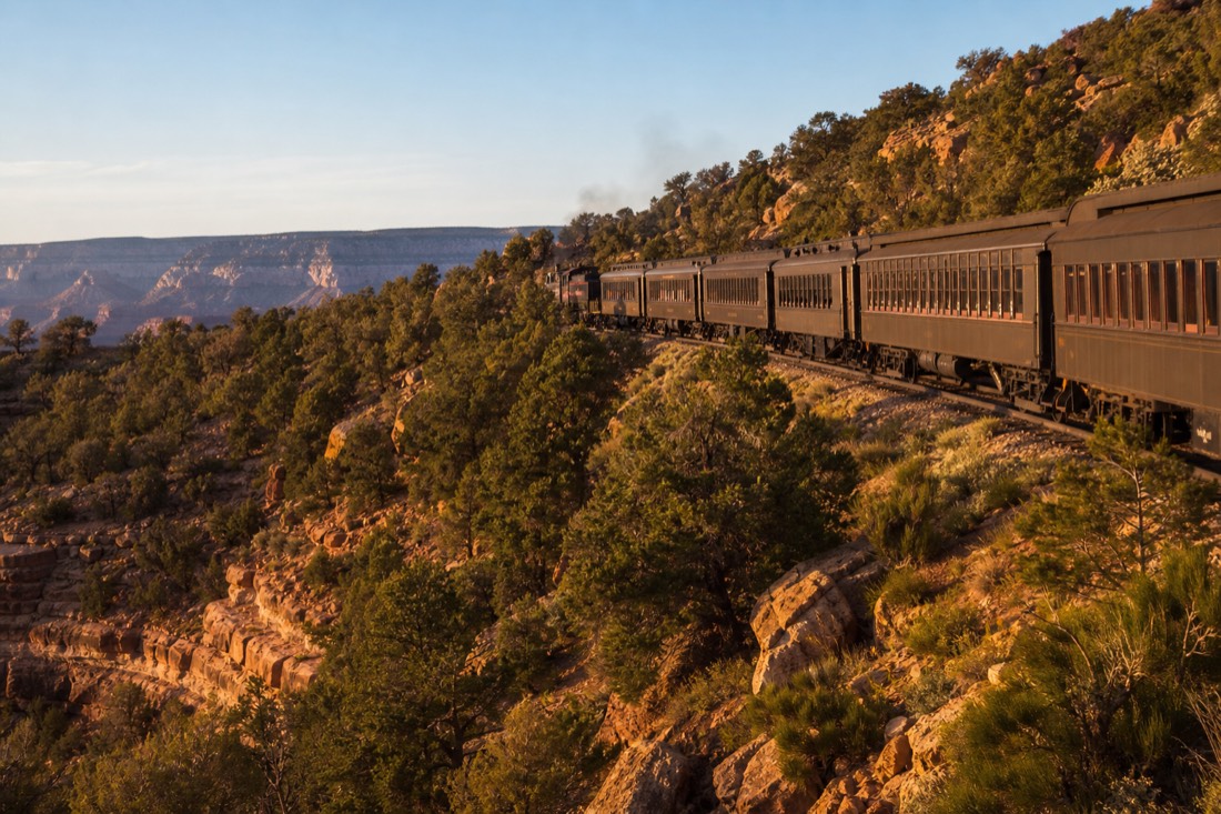Vintage railway carriages rolling through open pinyon and juniper country between Williams and the South Rim