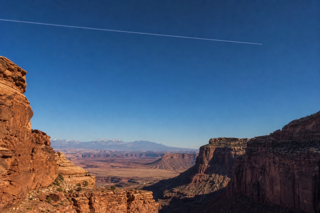 A modern airliner contrail crossing high above the desert in orderly controlled airspace