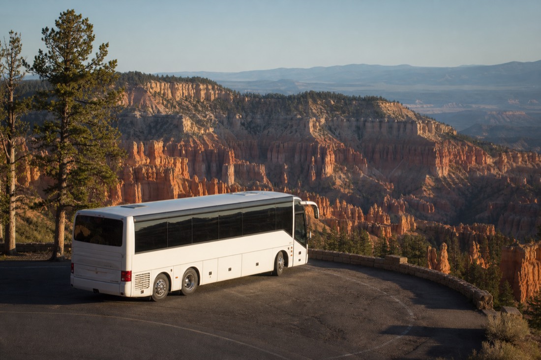 A touring coach parked beneath the pink hoodoo amphitheater rim at Bryce Canyon