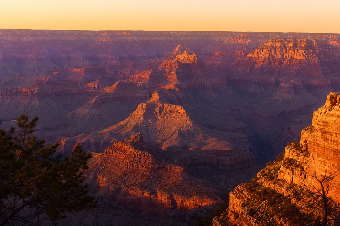 Deep orange sunset light raking across the buttes and temples of the Grand Canyon from the South Rim