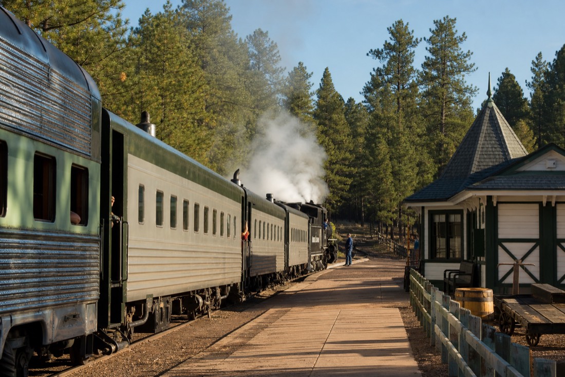 A restored vintage passenger train waiting at a small Arizona depot in morning light