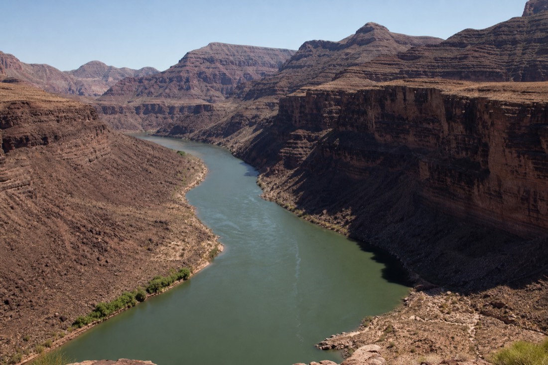 The Colorado River sweeping past Guano Point at Grand Canyon West under a clear blue sky