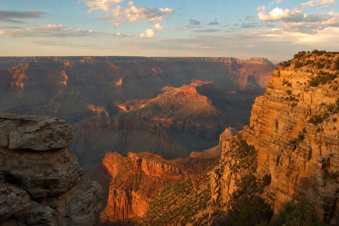 Golden late-afternoon light raking across the layered buttes of the Grand Canyon from a South Rim overlook in October