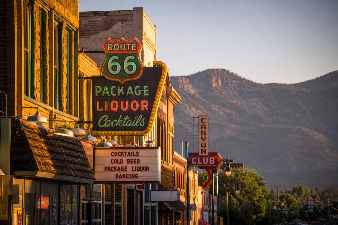 Historic Route 66 storefronts and neon signs in downtown Flagstaff on a summer evening