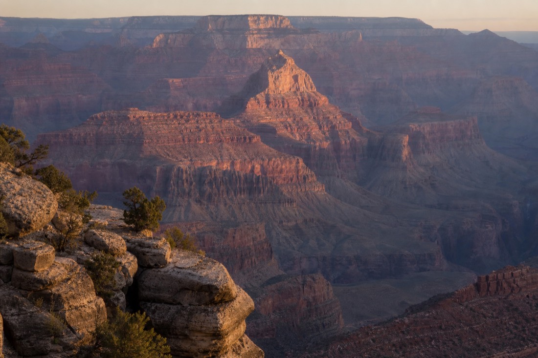 Early morning light hitting layered Grand Canyon buttes seen from a quiet South Rim viewpoint