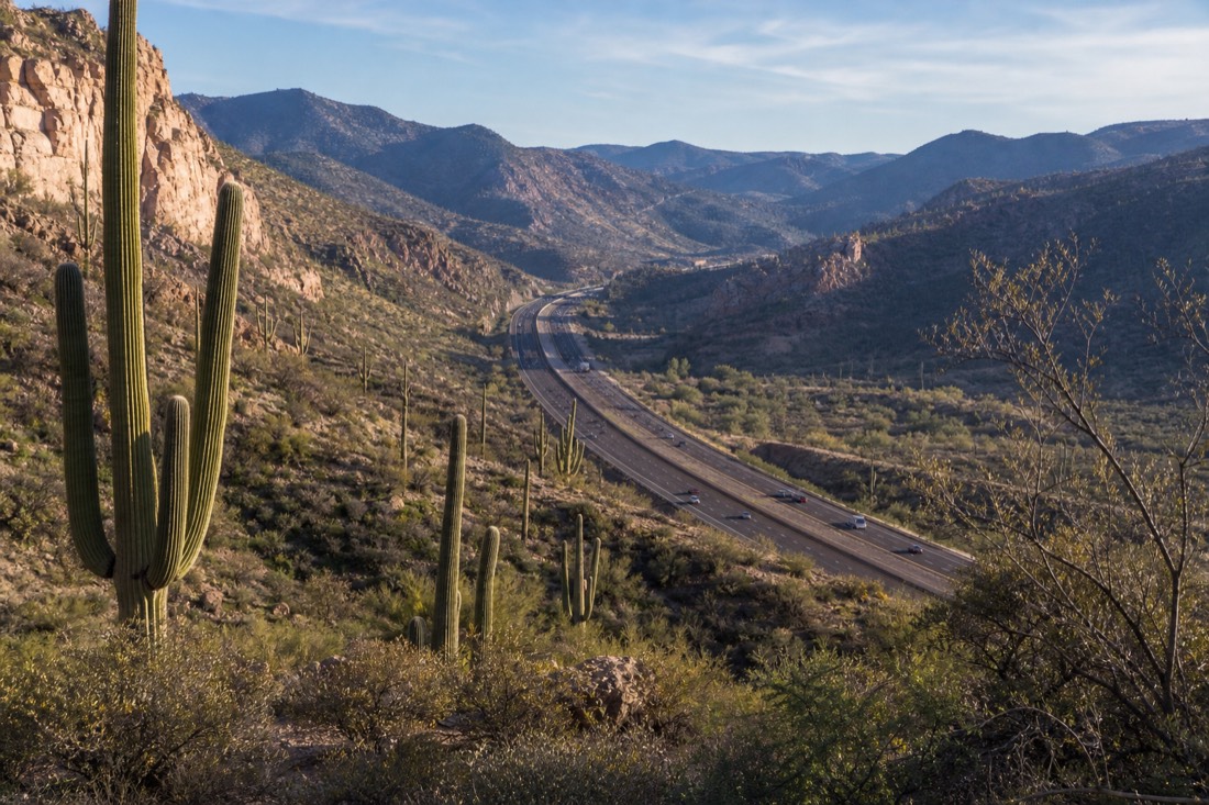 Interstate 17 climbing north out of the Sonoran Desert with saguaros in the foreground and pine hills ahead