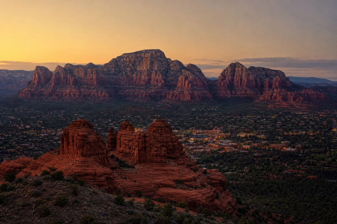 Sedona red rock buttes glowing at dusk with resort lights beginning to come on in the valley