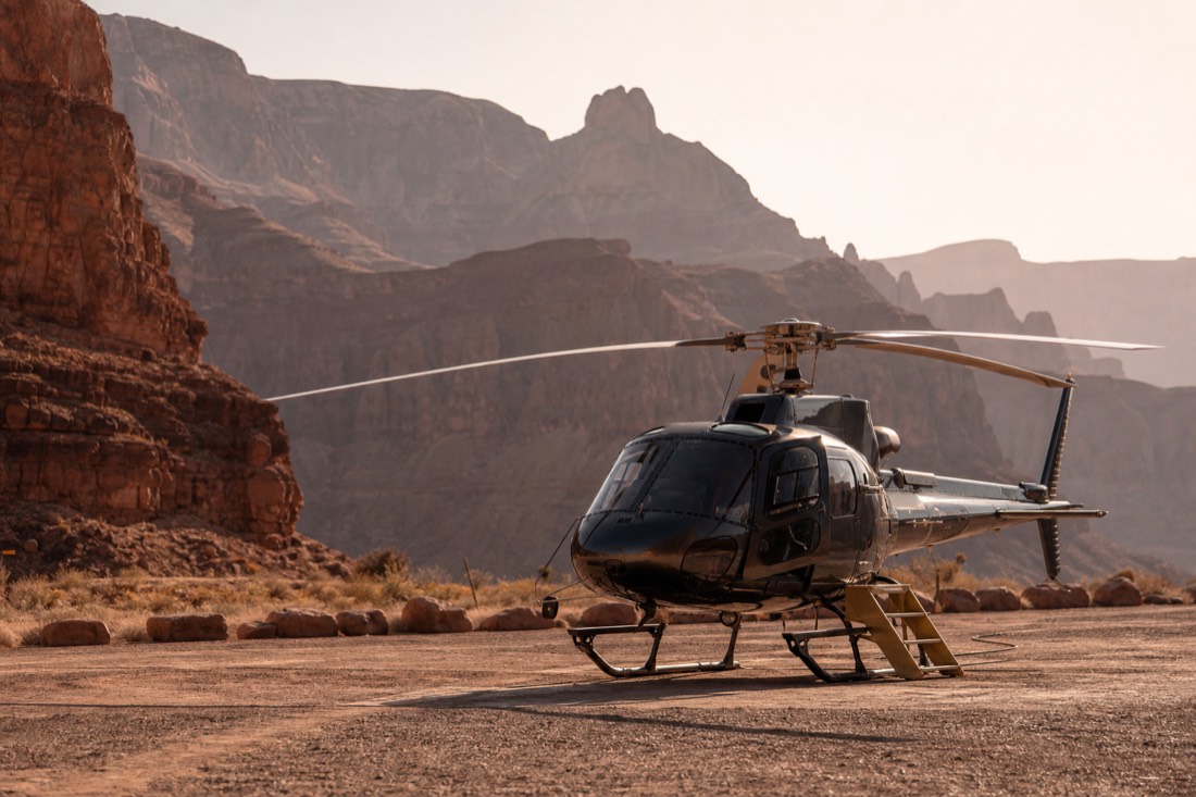 A helicopter resting on a desert pad with a small set of boarding steps beside the door