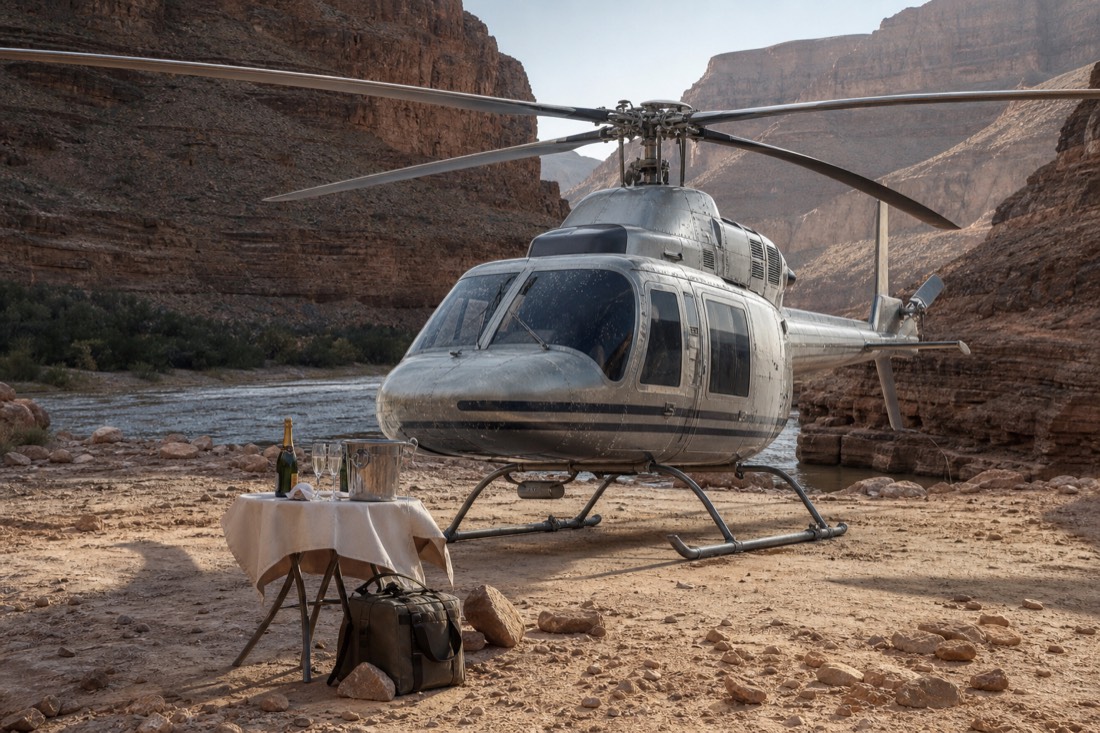A helicopter parked on a canyon-floor landing pad near the river with champagne set out on a small table