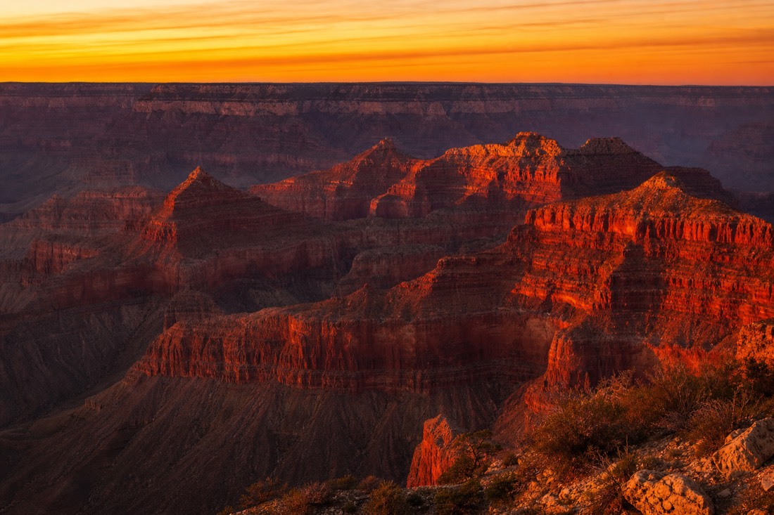 Sunset from Hopi Point with canyon buttes glowing deep red and the sky banded orange above the far rim