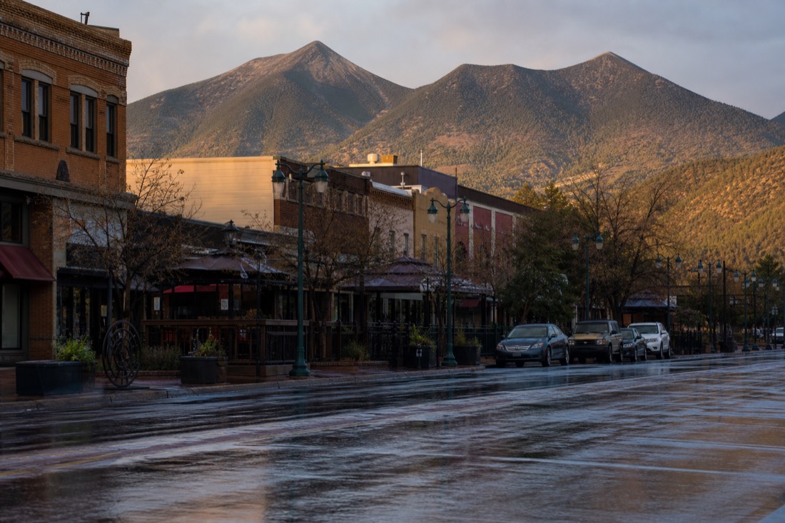 Historic downtown Flagstaff street in the evening with restaurant patios busy under the San Francisco Peaks